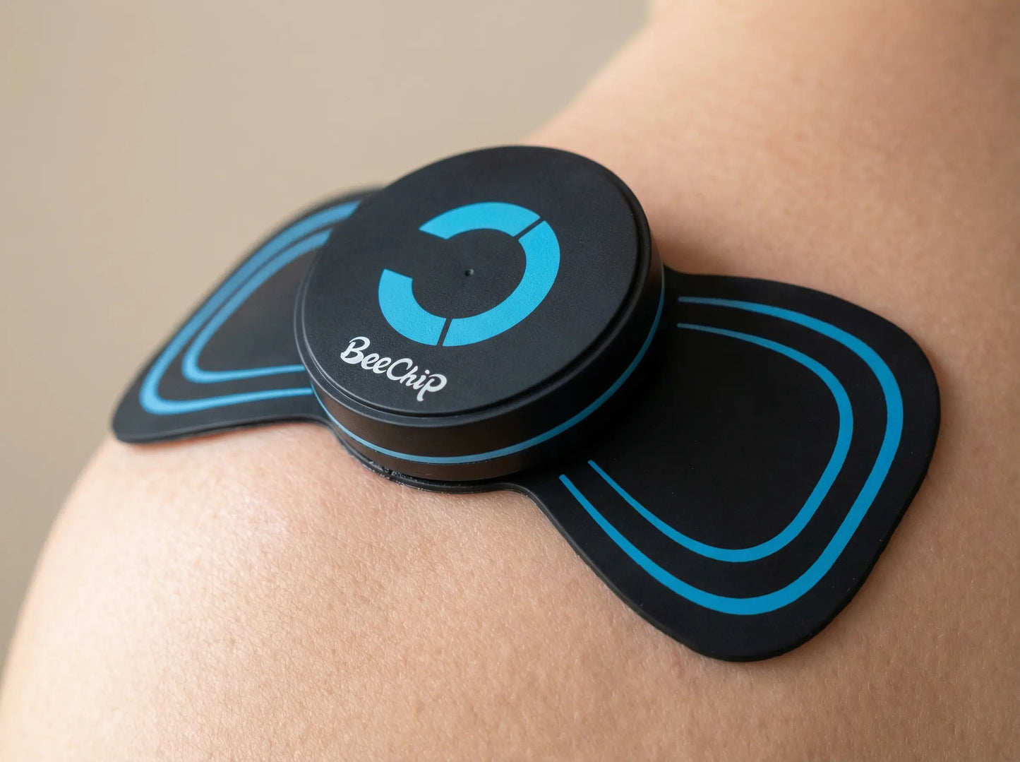 BackBalance BeeChip mini body massager for pain relief applied on shoulder with blue accents